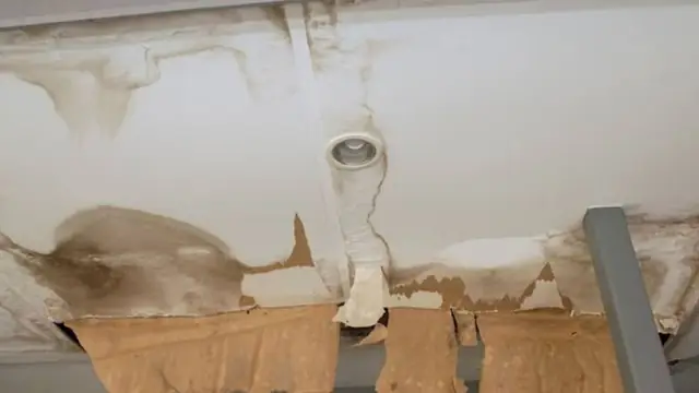 Water-stained ceiling around a light fixture with sagging, discolored drywall